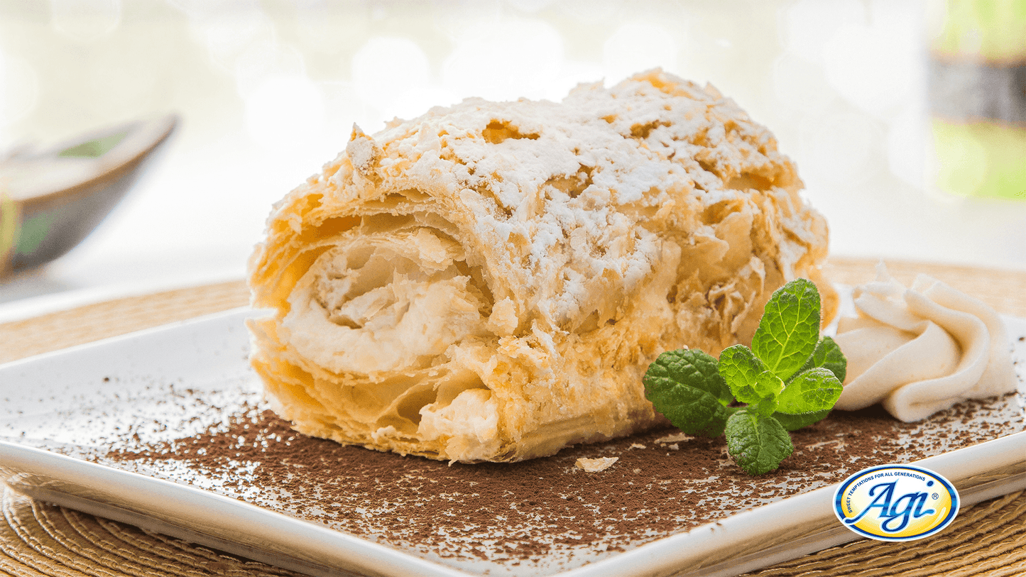 Frisches Napoleondessert mit Vanille-Creme auf Teller, dekoriert mit Minze und Puderzucker, perfekt für Dessertliebhaber.